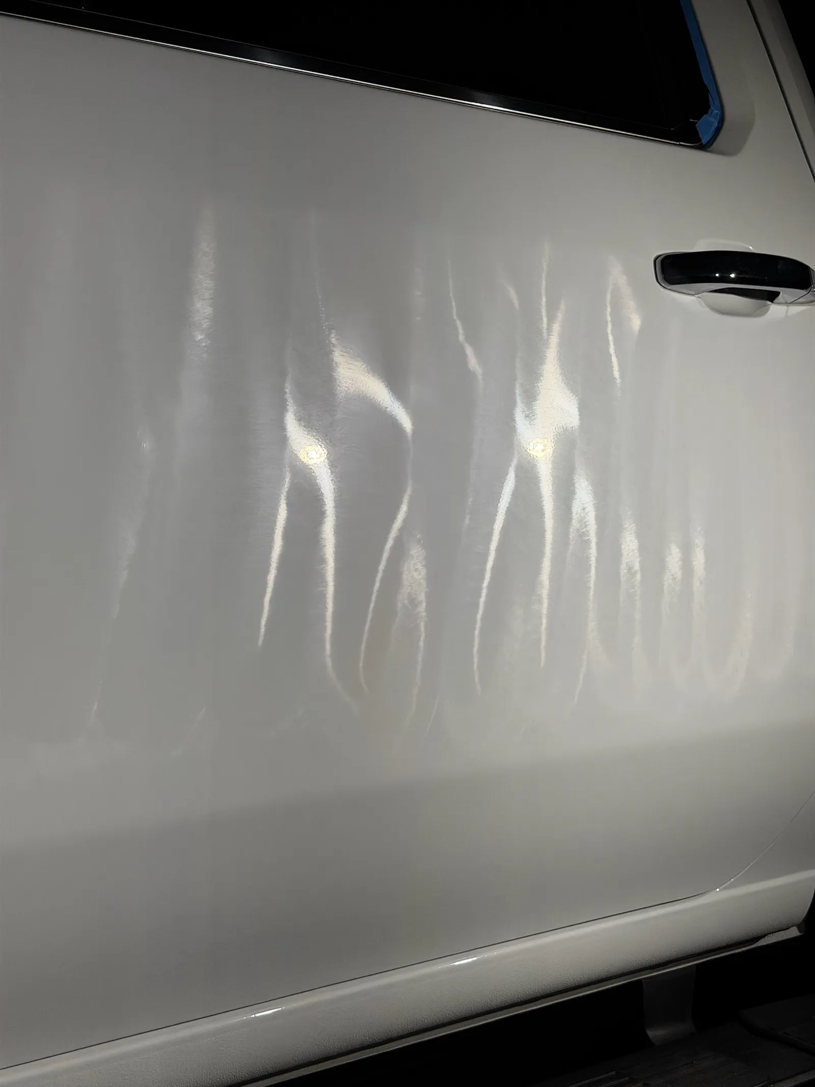 rear door of the white Silverado mid-correction, polish residue streaking the reflections